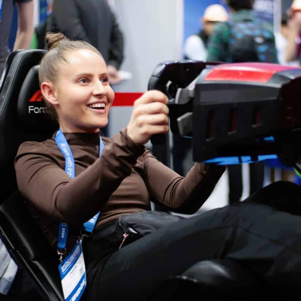 Very happy girl from Great Britain driving the Formula 1 motion simulator at a CloudFest.