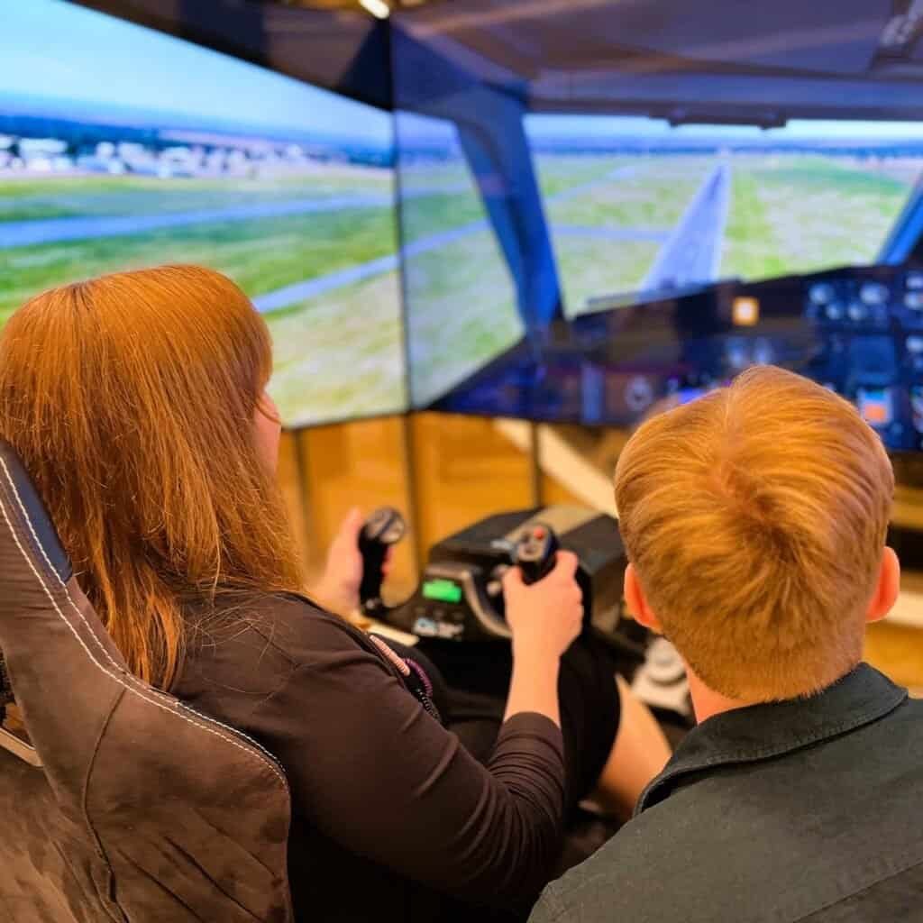 Two people have fun together on a flight simulator.